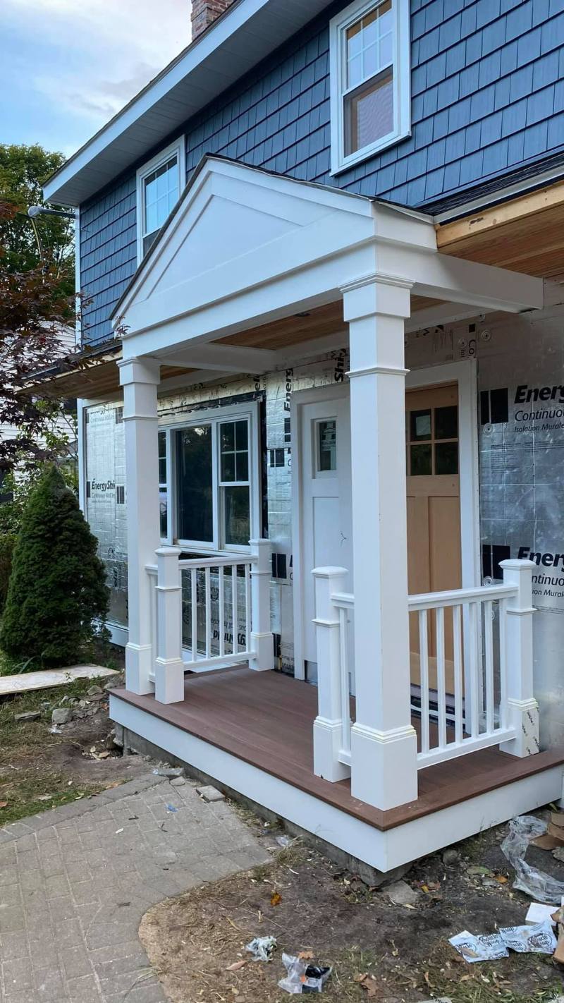A front porch with white columns, a pediment and a railing, finished with clean trim